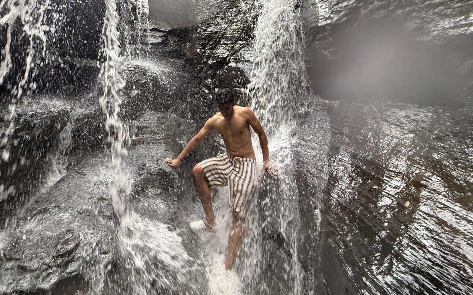 Kamil Hassan standing in a waterfall